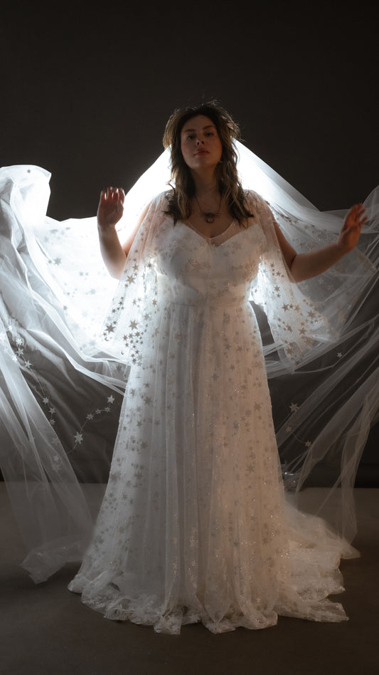 Two-piece ivory wedding dress with glowing star lace overlay plus size bride wearing romantic gown with veil and zodiac stars 